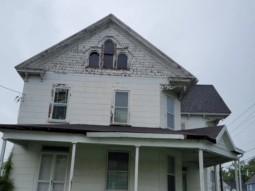 111 East Jewell Street before restoration: peeling paint, sagging porch roof, and rotted trim